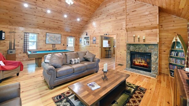 A cozy cabin interior with a pool table, leather sofa, fireplace, and bookshelves. - S`more Waggin` Cabin: Pet-Friendly--wifi, firepit, pool table (Blue Ridge)
