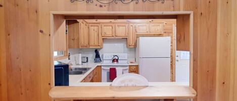 A kitchen with wooden cabinets, a white stove, and a refrigerator.