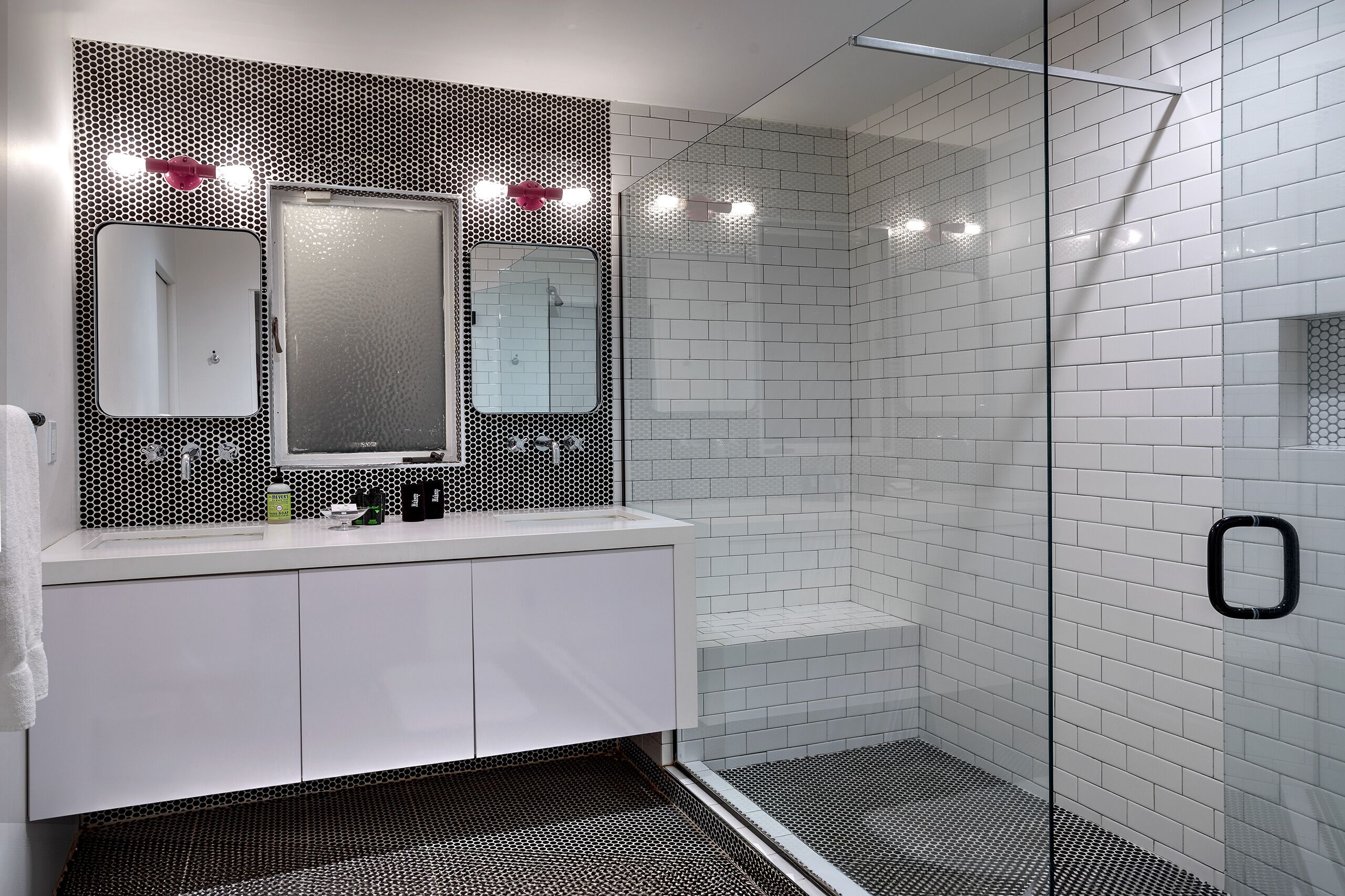 A modern bathroom with a white vanity, a large mirror, and a glass shower enclosure.