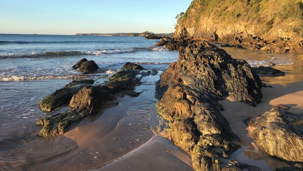 Una costa rocciosa con onde che lambiscono dolcemente le rocce.