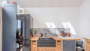 Ett modernt kök med ett inbyggt kylskåp, träskåp, en marmorbeklädd vägg bakom diskbänken och en diskho.