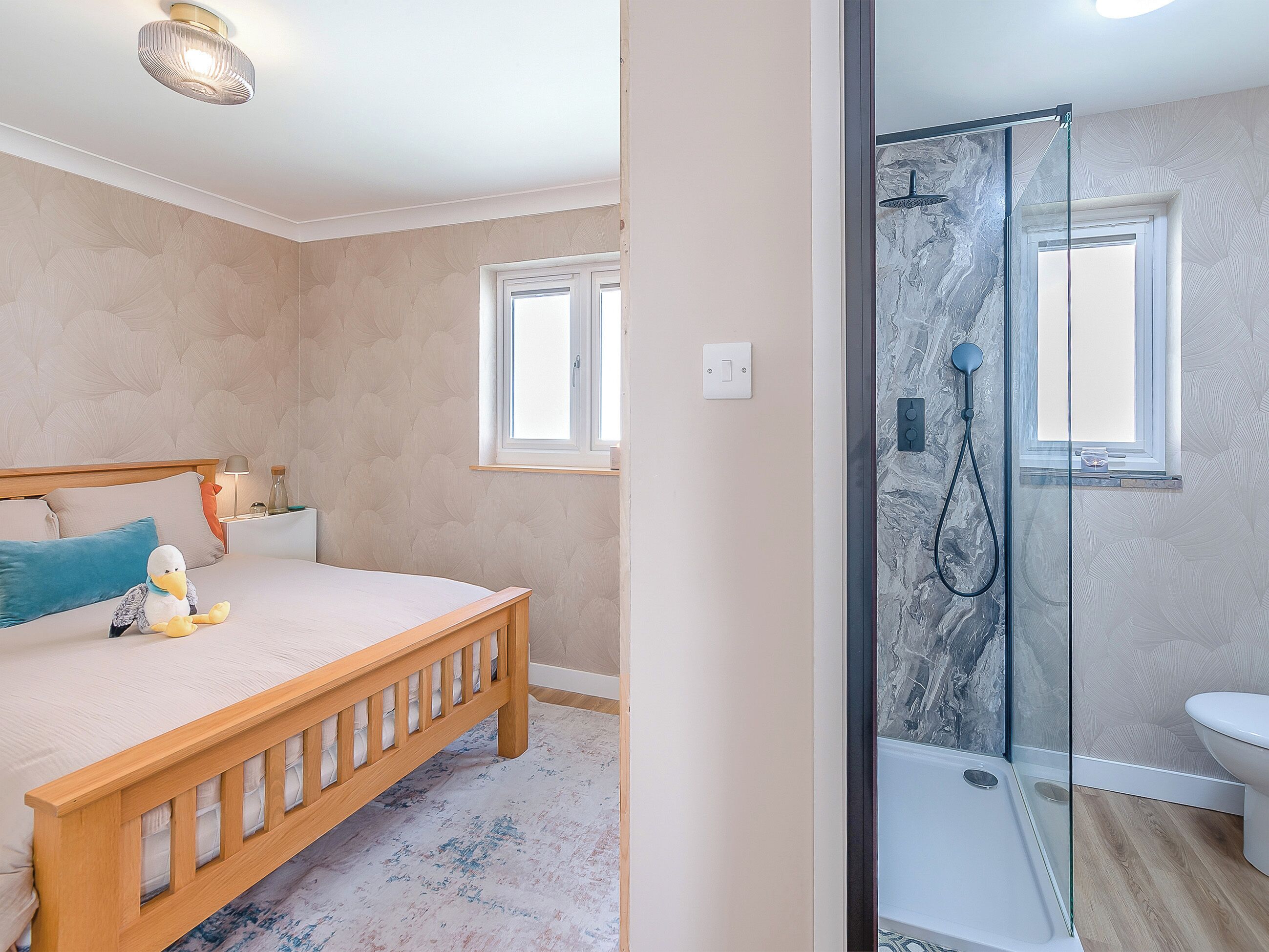 Une chambre à coucher avec un lit, une table de chevet, une lampe et un jouet en peluche.