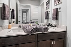 A bathroom with a white sink, dark wooden cabinets, and a large mirror.