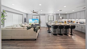 Una cocina moderna con una isla central, taburetes de bar y una zona de comedor.
