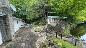 A rustic cabin with a stone exterior, a small porch, and a view of a lake. - Cottage Paradise - Water, Woods and Nature (Flesherton)