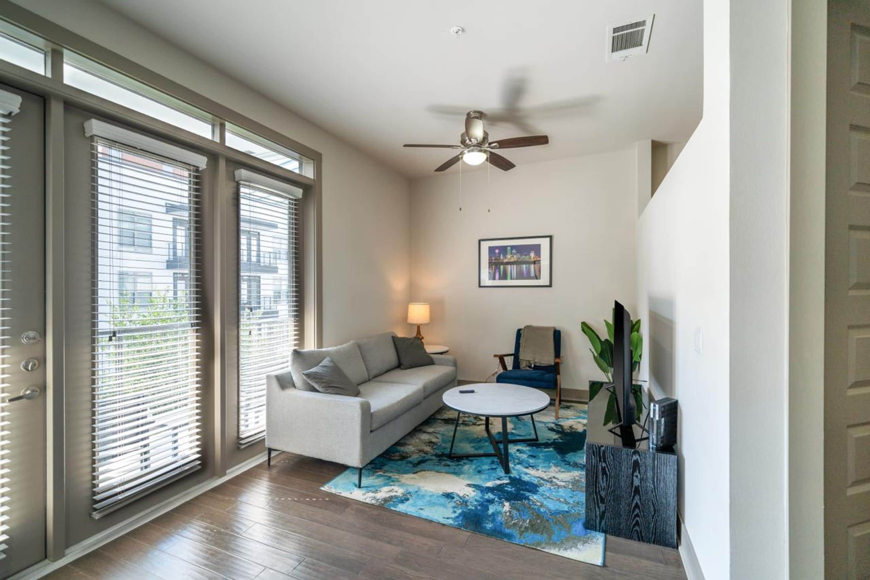A modern living room with a sofa, a coffee table, and a ceiling fan.