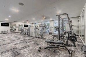Ein modernes Fitnessstudio mit verschiedenen Trainingsgeräten, Spiegeln und einem gemusterten Teppich.