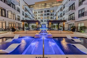 A modern hotel with a central pool area, multiple balconies, and a well-lit entrance. - Unwind at Cityline - Premium 1BR in Dallas (Plano)