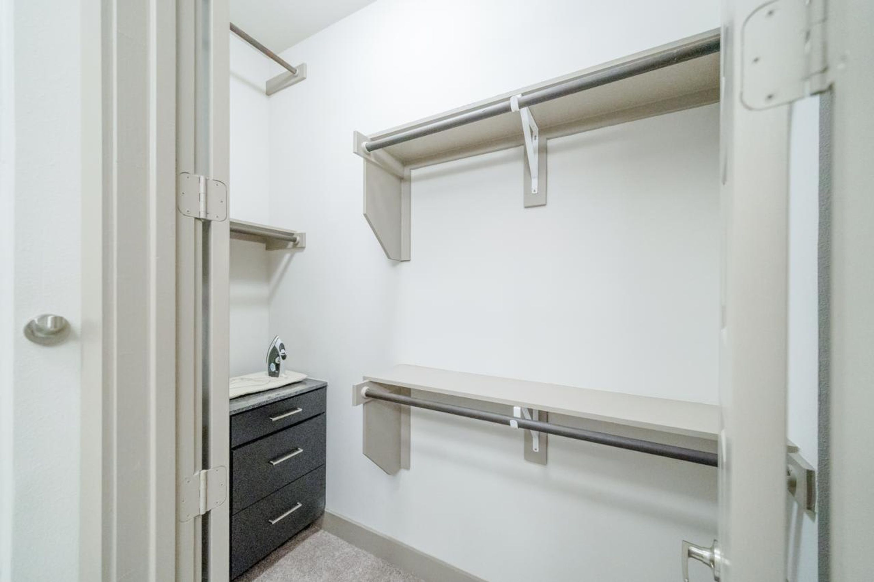 A walk-in closet with a vanity, drawers, and metal shelving units.