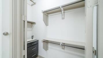 A walk-in closet with a vanity, drawers, and metal shelving units.
