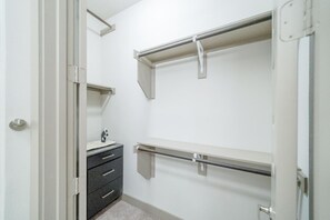 A walk-in closet with a vanity, drawers, and metal shelving units.