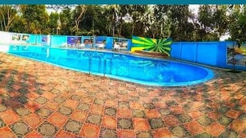 A swimming pool with a tiled deck and a colorful mural on the wall.
