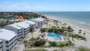 A beachfront hotel with multiple-story buildings, a swimming pool, and a beach view.