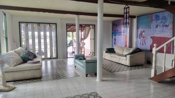 A spacious living area with a sofa, a chair, a fan, and a staircase.