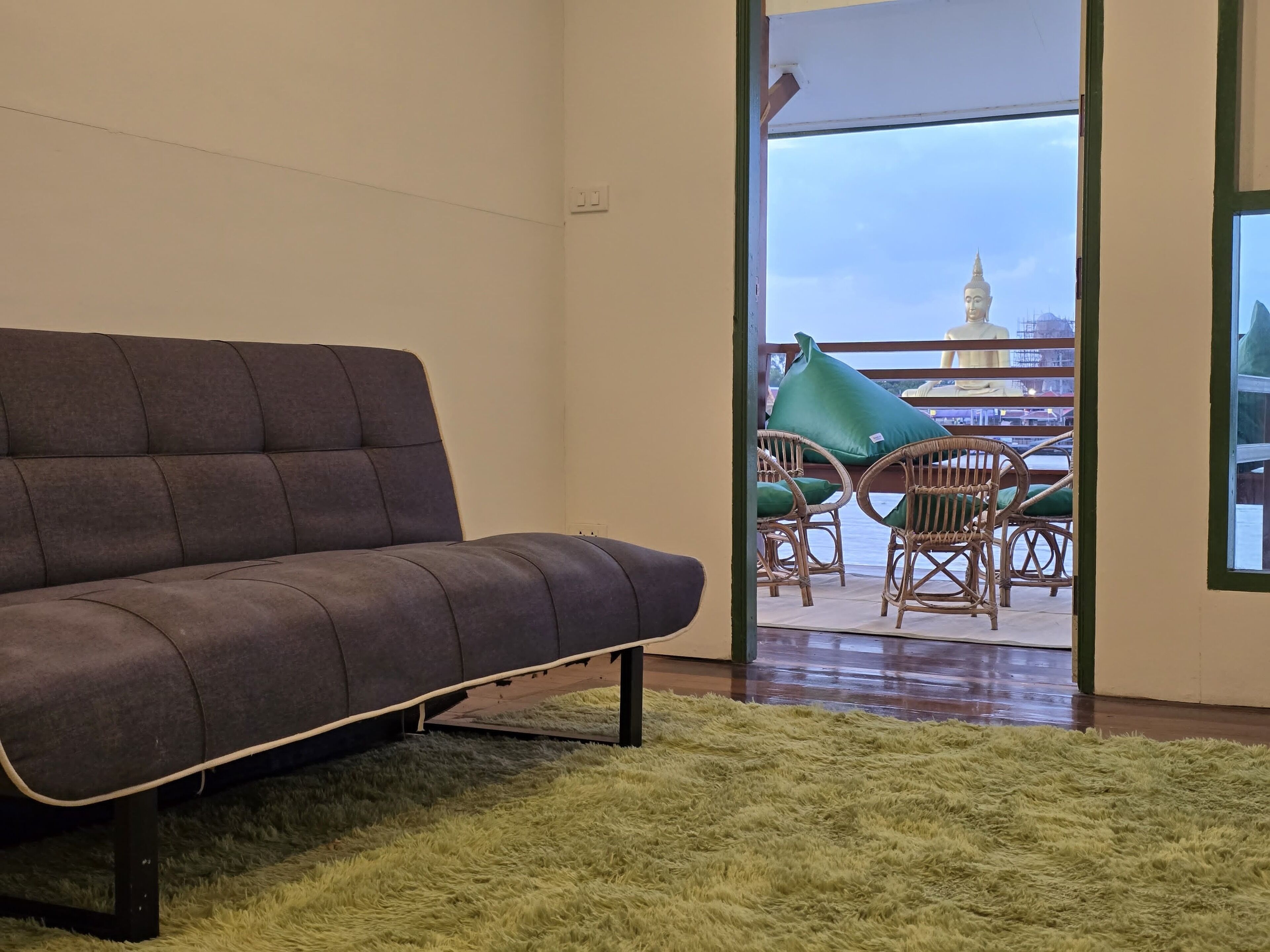 Una sala de estar moderna con un sofá gris, un tapete mullido color verde y sillones de mimbre.