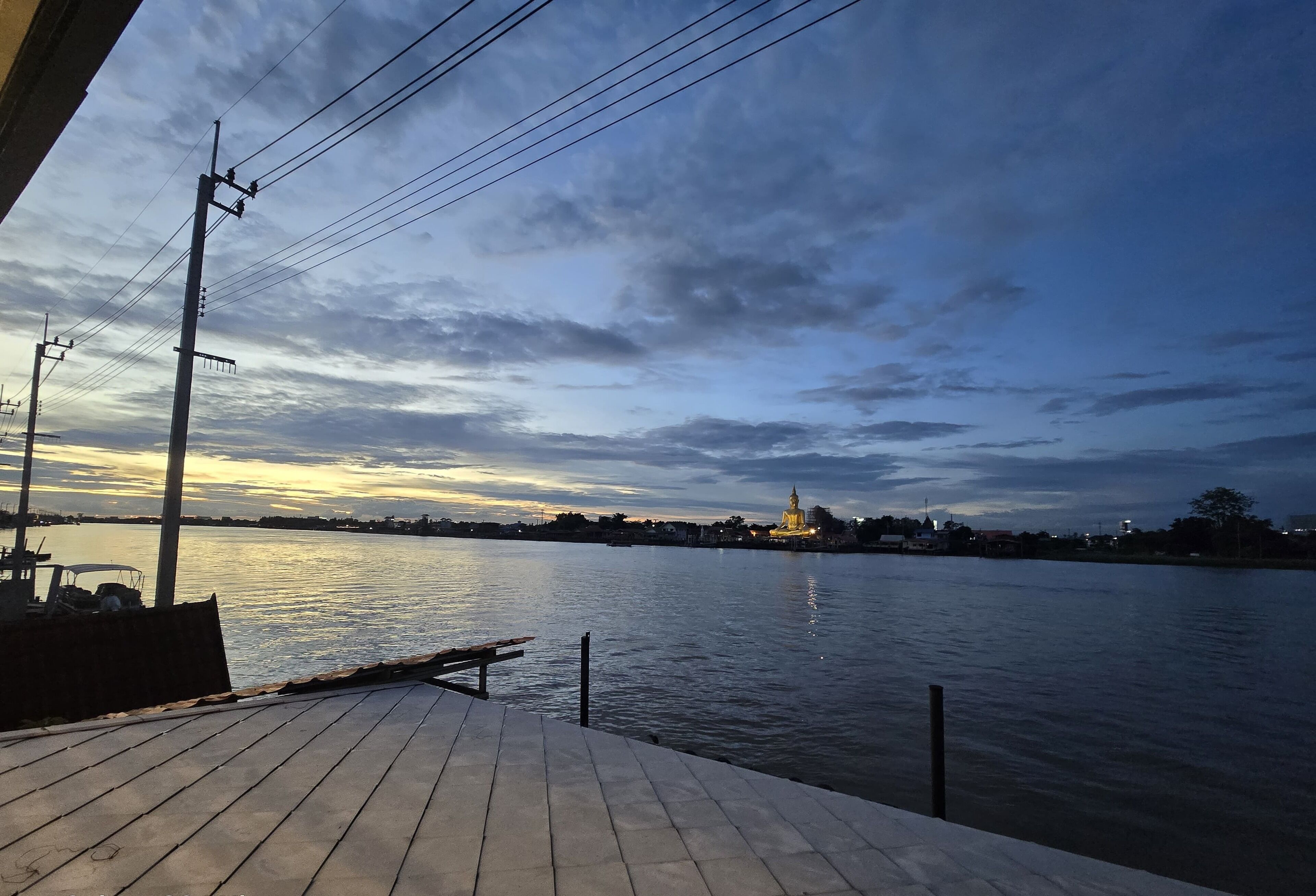 A wooden deck overlooking a river with a distant illuminated structure.