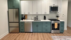 A kitchen with teal cabinets, a stainless steel refrigerator, a dishwasher, a stove, and a microwave.