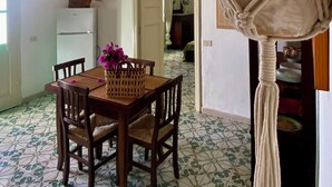 A dining area with a wooden table and chairs, a ceiling fan, and a macrame hanging plant.