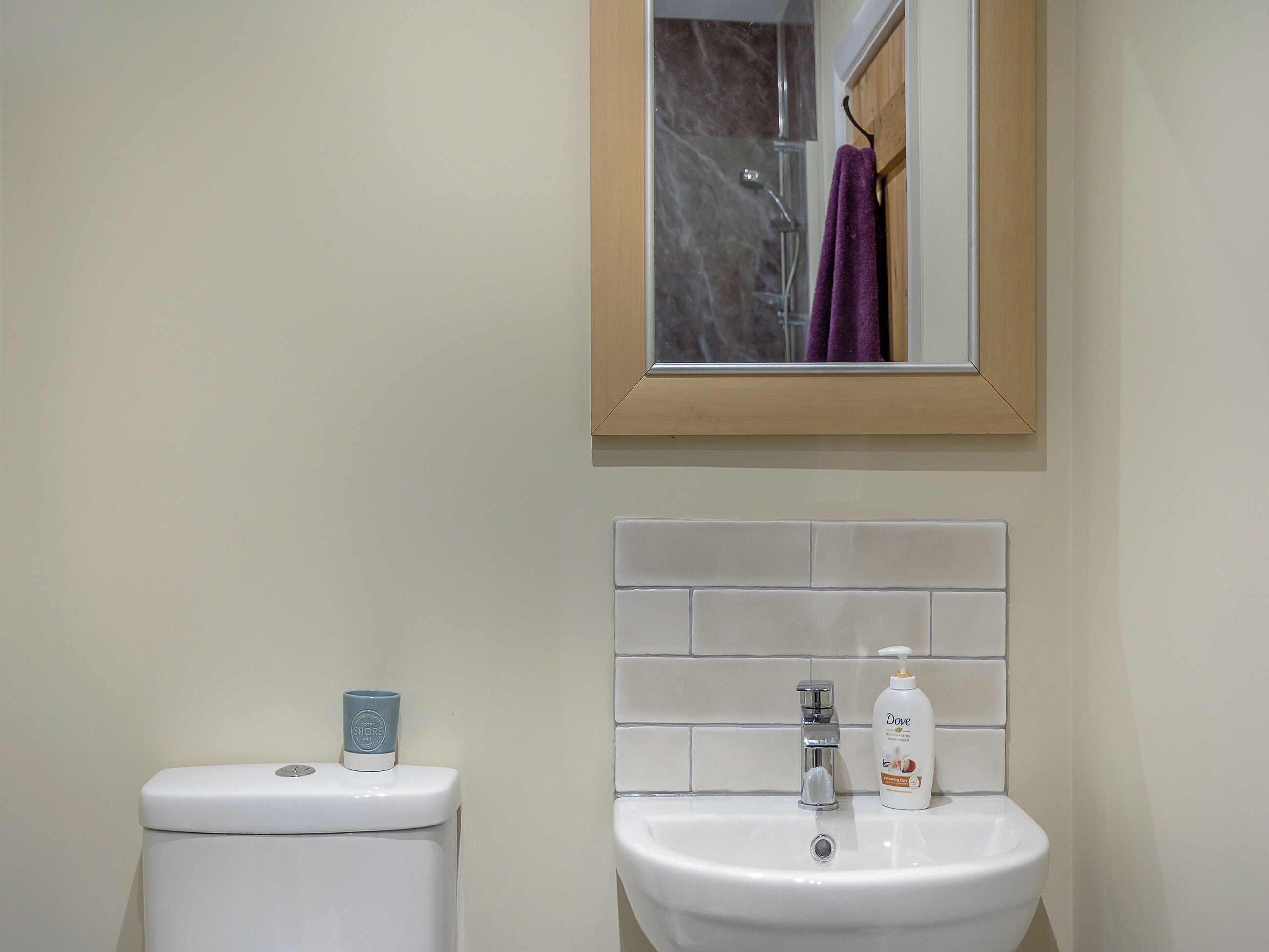 Een badkamer met toilet, wastafel, spiegel en een douche in de achtergrond.