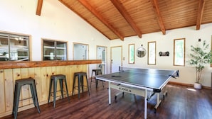 A ping pong table in a room with wooden floors and a high ceiling. - Wilderness West Resort Cabin 1 (Colville)