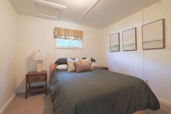 A bedroom with a bed, a nightstand, a lamp, and two framed pictures on the wall.