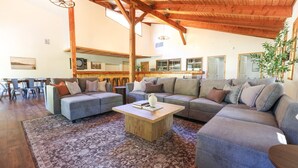 A spacious living area with a large sectional sofa, a coffee table, and a dining area with chairs. - Wilderness West Resort Cabin 2 (Colville)