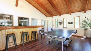 A ping pong table in a room with wooden floors and a high ceiling. - Wilderness West Resort Cabin 2 (Colville)