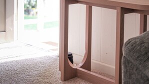 Une console en bois ornée d’un vase de fleurs, un tableau accroché au mur et une vue sur la verdure à l’extérieur.