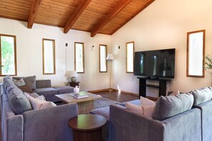 Ein Wohnzimmer mit einer Sofagarnitur, einem Couchtisch, einem Fernseher und gerahmten Bildern an der Wand.