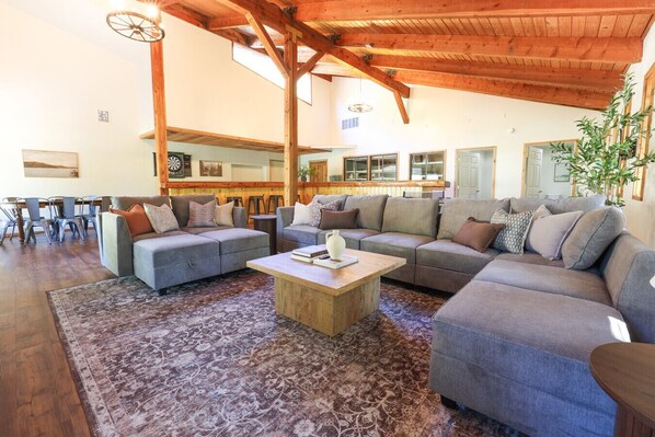 A spacious living area with a large sectional sofa, a coffee table, and a dining area with chairs.