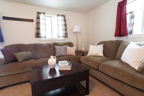 A living room with two brown sofas, a dark wooden coffee table, and a white vase.