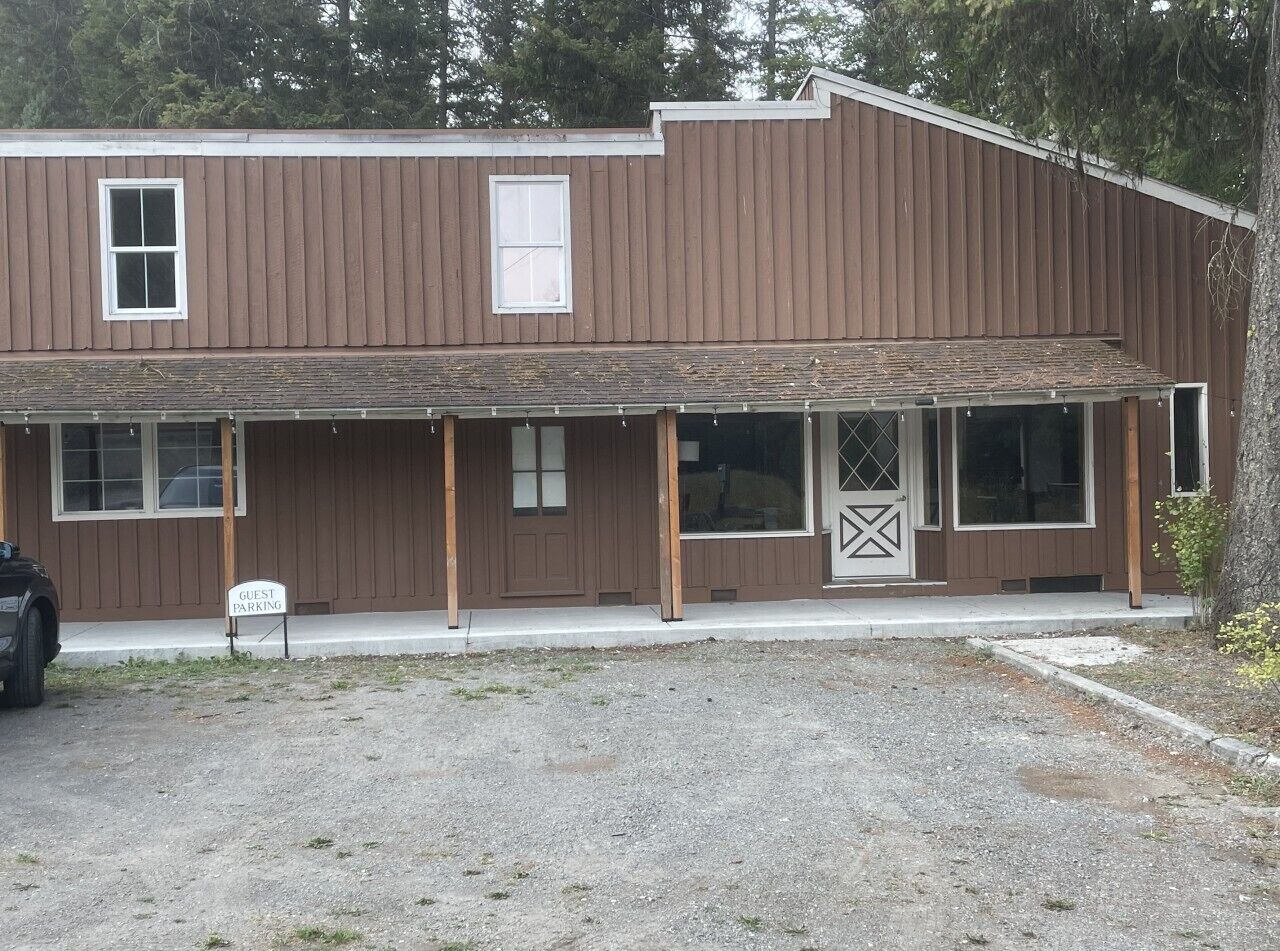 A two-story building with a covered porch and a guest parking sign.