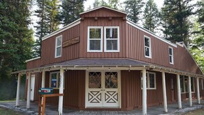 Un bâtiment en bois à deux étages, doté d’un porche, d’une boîte aux lettres et d’une enseigne indiquant qu’il s’agit d’un centre de villégiature situé en pleine nature.
