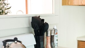 Una cocina con estufa blanca, hervidor y especiero con diversas especias.