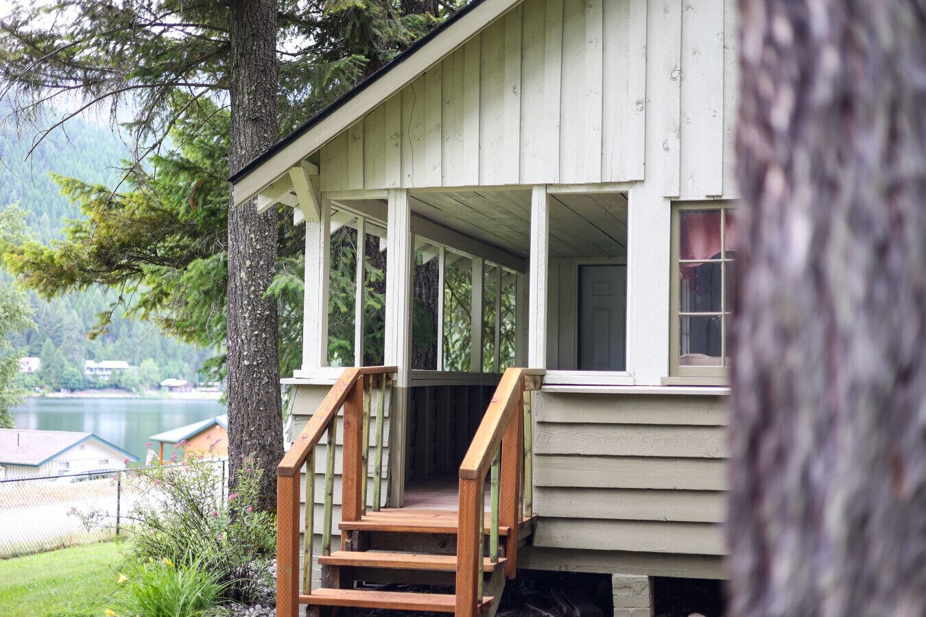 Eine Holzhütte mit Veranda, Treppe und Blick auf See und Wald.