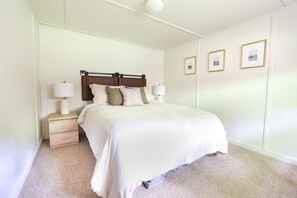 A neatly arranged bedroom with a large bed, two bedside tables with lamps, and three framed pictures on the wall. - Wilderness West Resort Cabin 6 (Colville)