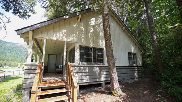 A wooden cabin with a porch and a staircase leading to the entrance. - Wilderness West Resort Cabin 7 (Colville)