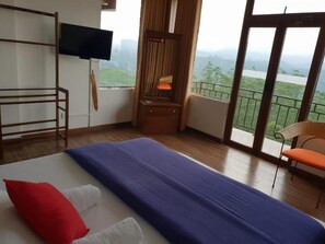 Quarto de hotel com cama, televisão, varanda e uma vista, e uma cadeira.