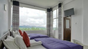 A bedroom with two beds, a TV, and a view of the outdoors. - Daynish Rock Bungalow (Hatton)