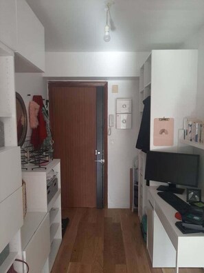 A room with a wooden door, a desk with a computer, and a white shelving unit. - Quiet Garden-Facing Retreat (Paris)