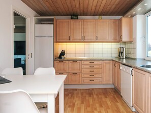 A modern kitchen with wooden cabinets, a white countertop, and a built-in dishwasher. - 4 Star Holiday Home in Bronderslev (Bronderslev)