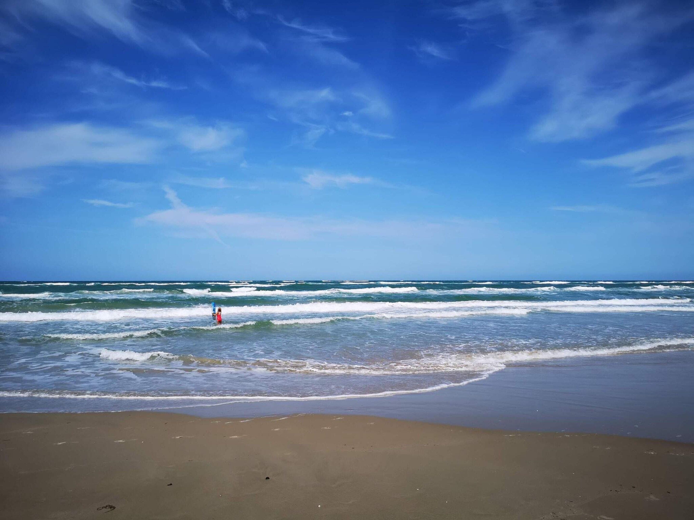 A beach with waves and a clear sky.
