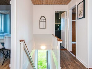 A hallway with a wooden ceiling, a white wall with a window, and a door leading to a room with a dark floor. - 4 Star Holiday Home in Bronderslev (Bronderslev)