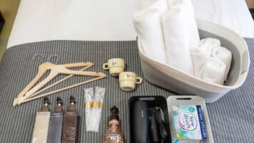 A neatly arranged set of toiletries and a bowl of towels on a bed.