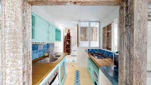 A narrow kitchen with teal cabinets, a wooden countertop, and a blue and white checkered floor. - Villa Kendal Seminyak (Seminyak)