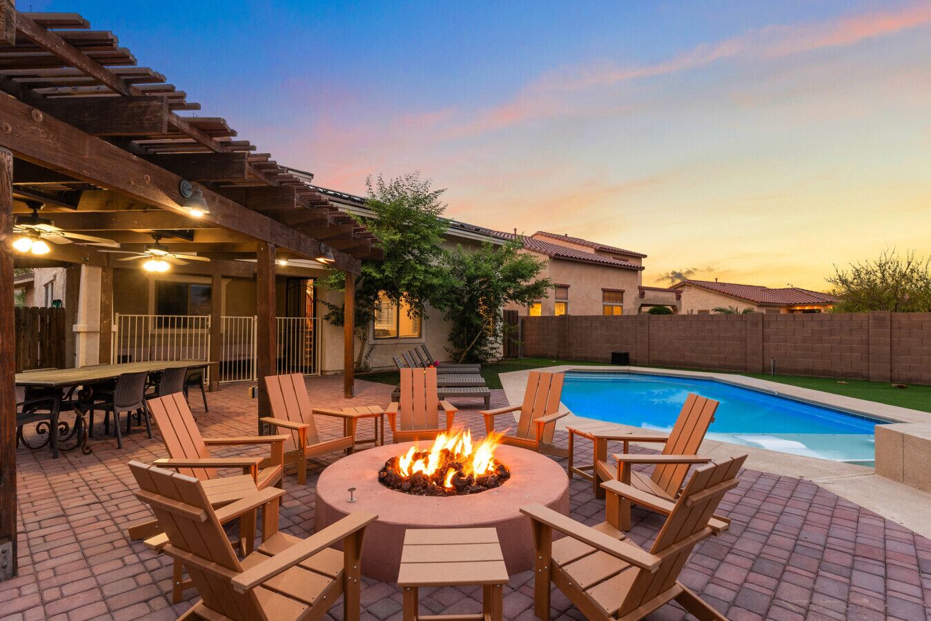 An outdoor patio with a fire pit, seating, and a swimming pool.