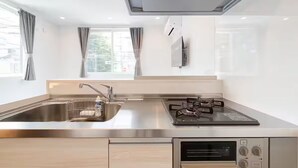 Une cuisine moderne dotée d’un évier en acier inoxydable, d’une cuisinière encastrée et d’un four à micro-ondes.
