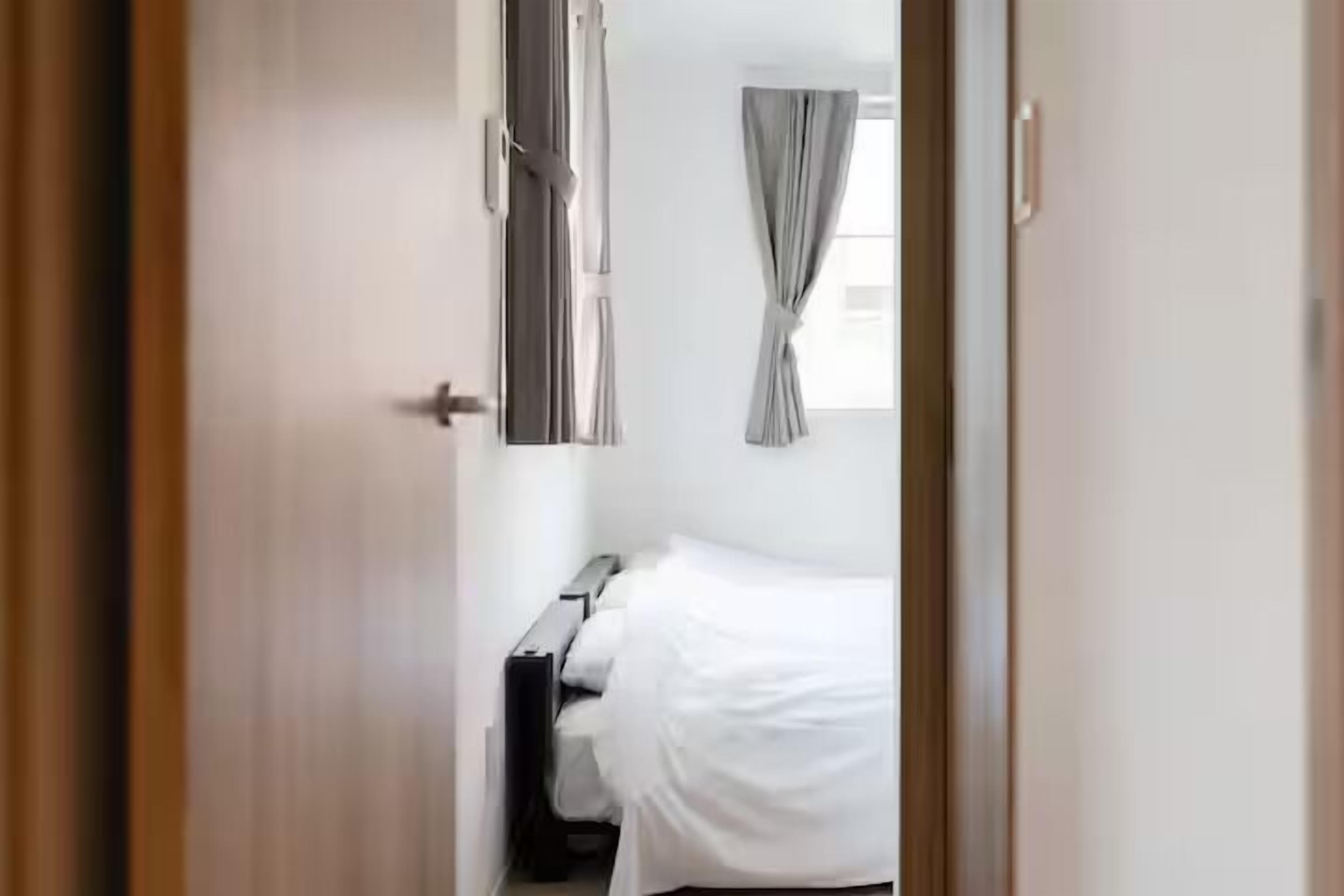 A bedroom with a bed, a bedside table, and curtains.