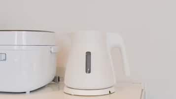 A white electric kettle and a white rice cooker on a white countertop.