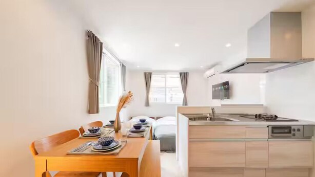 Une cuisine moderne avec un coin repas, comprenant une table en bois, des chaises et une cuisinière encastrée.